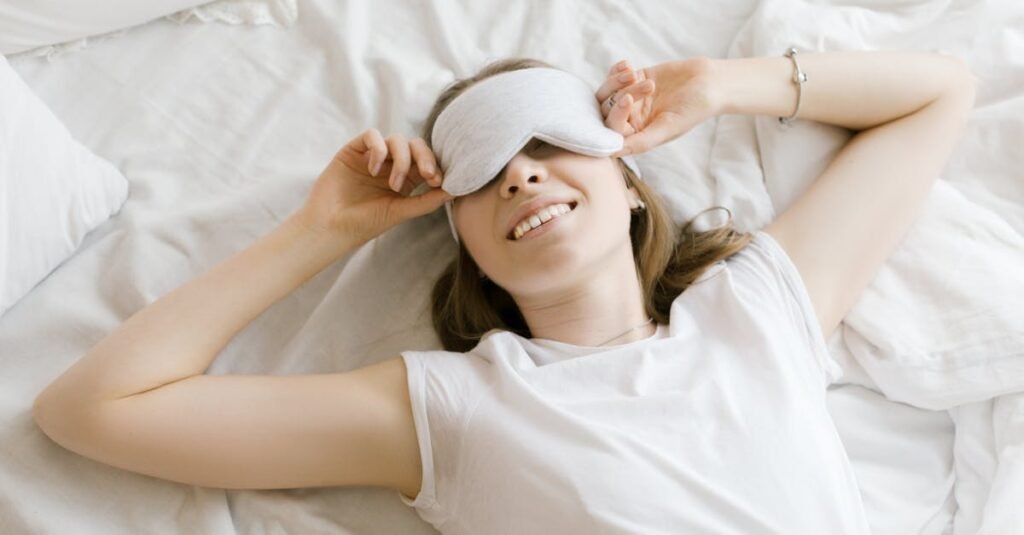 A serene young woman enjoying relaxation with a sleep mask in her cozy bed.